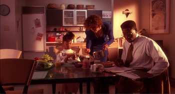 Movie still from “Jungle Fever” (1991), directed by Spike Lee – A woman and two children sitting at a dining table; Medium shot, High angle