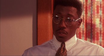 Movie still from “Jungle Fever” (1991), directed by Spike Lee – A person wearing glasses and a tie; Close Up shot, Over the shoulder angle