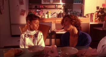 Movie still from “Jungle Fever” (1991), directed by Spike Lee – Two people sitting at a table with a plate of food; Medium shot, High angle
