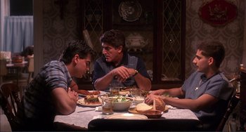 Movie still from “Jungle Fever” (1991), directed by Spike Lee – A group of people sitting at a table with food on it; Medium shot, High angle