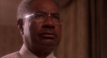 Movie still from “Jungle Fever” (1991), directed by Spike Lee – An older man wearing glasses and a white shirt; Close Up shot, Low angle