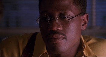 Movie still from “Jungle Fever” (1991), directed by Spike Lee – A person wearing glasses and a yellow shirt; Close Up shot, Low angle