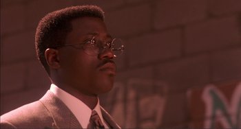 Movie still from “Jungle Fever” (1991), directed by Spike Lee – A person wearing a suit and glasses; Close Up shot, Low angle