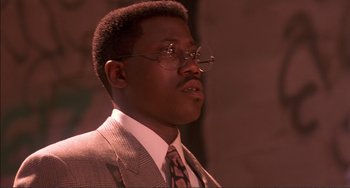 Movie still from “Jungle Fever” (1991), directed by Spike Lee – A man in a suit and tie wearing glasses; Close Up shot, Low angle