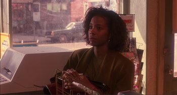 Movie still from “Jungle Fever” (1991), directed by Spike Lee – A woman sitting at a table in front of a window; Close Up shot, Low angle