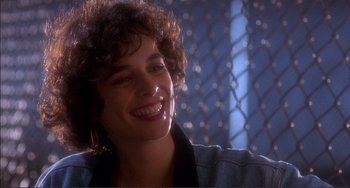 Movie still from “Jungle Fever” (1991), directed by Spike Lee – A woman with curly brown hair smiling for the camera; Close Up shot, Over the shoulder angle