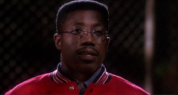Movie still from “Jungle Fever” (1991), directed by Spike Lee – A person wearing glasses and a red sweater; Close Up shot, Low angle