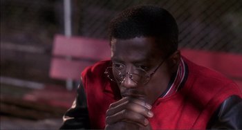 Movie still from “Jungle Fever” (1991), directed by Spike Lee – A man in a red shirt is holding his hands together; Close Up shot, High angle