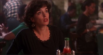 Movie still from “Jungle Fever” (1991), directed by Spike Lee – A woman sitting in front of a bottle of juice; Close Up shot, Over the shoulder angle