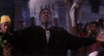 Movie still from “Jungle Fever” (1991), directed by Spike Lee – A man standing in the middle of a room with his arms outstreched; Medium shot, Low angle