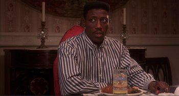 Movie still from “Jungle Fever” (1991), directed by Spike Lee – A man sitting at a table with a drink in front of him; Medium shot, High angle