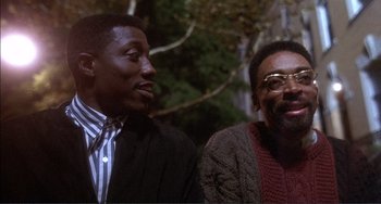 Movie still from “Jungle Fever” (1991), directed by Spike Lee – Two men sitting next to each other in a forest; Close Up shot, Low angle