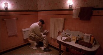 Movie still from “Jungle Fever” (1991), directed by Spike Lee – A man sitting on top of a toilet in a bathroom; Wide shot, High angle