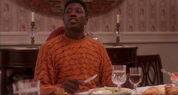 Movie still from “Jungle Fever” (1991), directed by Spike Lee – A man sitting at a dinner table with a knife and fork; Medium shot, High angle