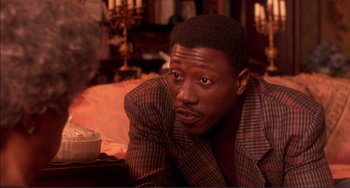 Movie still from “Jungle Fever” (1991), directed by Spike Lee – A man in a suit sitting on a bed; Close Up shot, Over the shoulder angle
