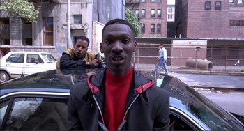 Movie still from “Jungle Fever” (1991), directed by Spike Lee – A man in a black jacket standing next to a car; Medium shot, Low angle