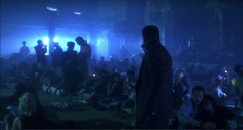 Movie still from “Jungle Fever” (1991), directed by Spike Lee – A crowd of people sitting and standing in a dark room; Wide shot, High angle