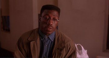 Movie still from “Jungle Fever” (1991), directed by Spike Lee – A man in a brown jacket wearing glasses and a blue shirt; Close Up shot, High angle