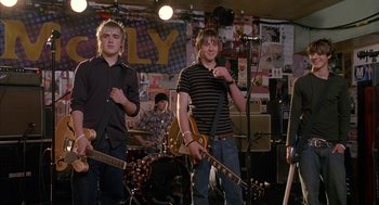 Movie still from “Just My Luck” (2006), directed by Donald Petrie – A group of young men standing in front of a microphone; Medium shot, Over the shoulder angle