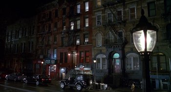 Movie still from “Just My Luck” (2006), directed by Donald Petrie – A jeep parked on the side of the road in front of a building; Extreme Wide shot, High angle