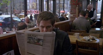 Movie still from “Just My Luck” (2006), directed by Donald Petrie – A man sitting at a table reading a newspaper; Close Up shot, Over the shoulder angle