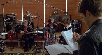 Movie still from “Just My Luck” (2006), directed by Donald Petrie – A group of young men playing instruments in a recording studio; Wide shot, High angle