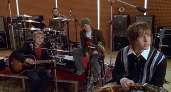 Movie still from “Just My Luck” (2006), directed by Donald Petrie – A group of young men sitting in a recording studio; Medium shot, High angle