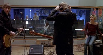 Movie still from “Just My Luck” (2006), directed by Donald Petrie – A man standing in front of a guitar in a room; Wide shot, Over the shoulder angle