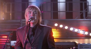 Movie still from “Just My Luck” (2006), directed by Donald Petrie – A man in a suit and a tie is singing; Medium shot, Low angle