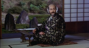 Movie still from “Kagemusha” (1980), directed by Akira Kurosawa – A man sitting on the ground wearing a robe; Medium shot, High angle