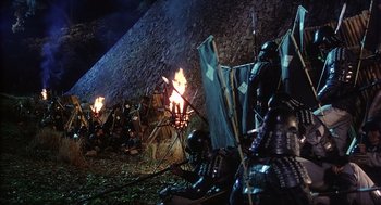 Movie still from “Kagemusha” (1980), directed by Akira Kurosawa – A group of people standing next to a fire; Wide shot, High angle
