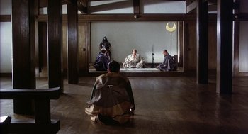 Movie still from “Kagemusha” (1980), directed by Akira Kurosawa – A group of people sitting on the ground in a room; Wide shot, High angle