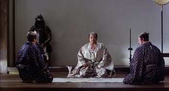 Movie still from “Kagemusha” (1980), directed by Akira Kurosawa – A man sitting on the ground wearing a robe; Wide shot, High angle