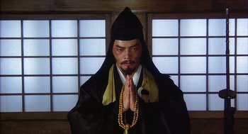 Movie still from “Kagemusha” (1980), directed by Akira Kurosawa – A man in a monk's outfit praying with his hands folded together; Medium shot, Low angle
