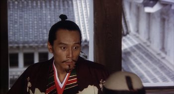 Movie still from “Kagemusha” (1980), directed by Akira Kurosawa – A man in a traditional asian outfit smoking a pipe; Close Up shot, Low angle