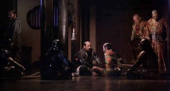 Movie still from “Kagemusha” (1980), directed by Akira Kurosawa – A group of men sitting on the floor of a building; Wide shot, High angle