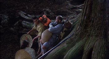 Movie still from “Kagemusha” (1980), directed by Akira Kurosawa – Two men are climbing up a tree trunk; Wide shot, High angle