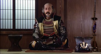 Movie still from “Kagemusha” (1980), directed by Akira Kurosawa – A man sitting on the ground wearing armor; Medium shot, High angle