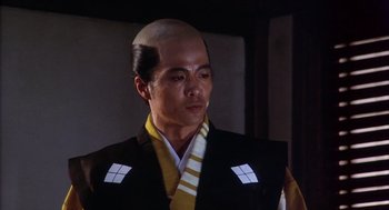 Movie still from “Kagemusha” (1980), directed by Akira Kurosawa – A man with a shaved head and a yellow and black outfit; Close Up shot, Low angle