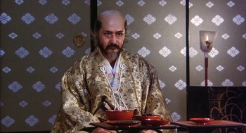 Movie still from “Kagemusha” (1980), directed by Akira Kurosawa – A man in a kimono holding a tray of food; Medium shot, Low angle