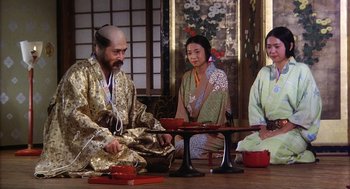 Movie still from “Kagemusha” (1980), directed by Akira Kurosawa – A group of people sitting around a wooden table; Medium shot, High angle