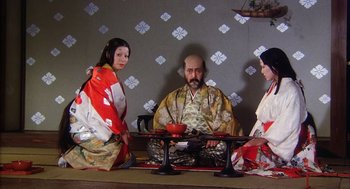 Movie still from “Kagemusha” (1980), directed by Akira Kurosawa – A man and two women sitting in front of a table; Medium shot, High angle