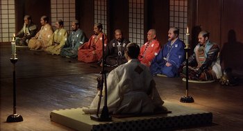 Movie still from “Kagemusha” (1980), directed by Akira Kurosawa – A group of men sitting in a circle on the floor; Wide shot, High angle