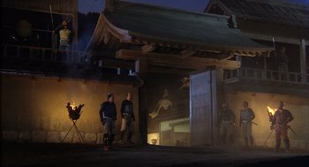 Movie still from “Kagemusha” (1980), directed by Akira Kurosawa – Three people standing in a courtyard at night; Wide shot, Low angle