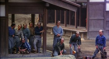 Movie still from “Kagemusha” (1980), directed by Akira Kurosawa – A group of men sitting on the ground in front of a building; Wide shot, High angle