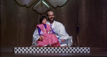 Movie still from “Kagemusha” (1980), directed by Akira Kurosawa – A man and a little girl sitting on a stage; Wide shot, Low angle