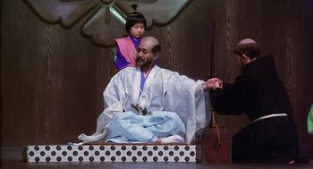 Movie still from “Kagemusha” (1980), directed by Akira Kurosawa – A man sitting on a stage with a child; Medium shot, High angle