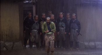 Movie still from “Kagemusha” (1980), directed by Akira Kurosawa – A group of men standing next to each other in front of a building; Wide shot, Low angle