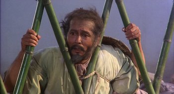 Movie still from “Kagemusha” (1980), directed by Akira Kurosawa – A man with a beard is holding a bunch of bamboo sticks; Medium shot, Low angle