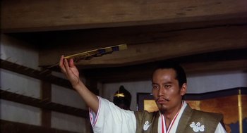 Movie still from “Kagemusha” (1980), directed by Akira Kurosawa – A man in traditional japanese garb holding a fan in his hand; Medium shot, Low angle